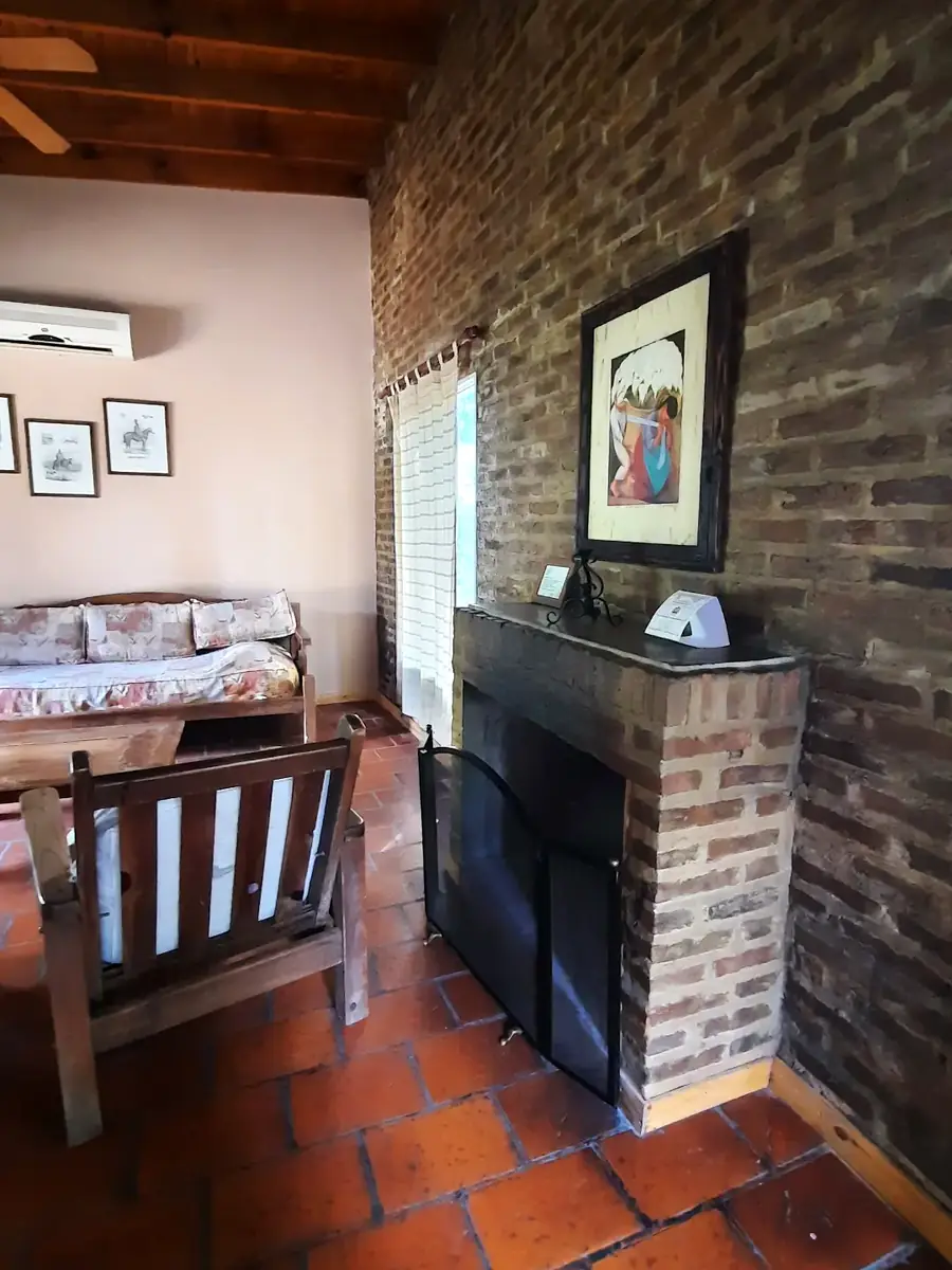 El living con hogar a leña en la pared de ladrillo, en El Ceibo.