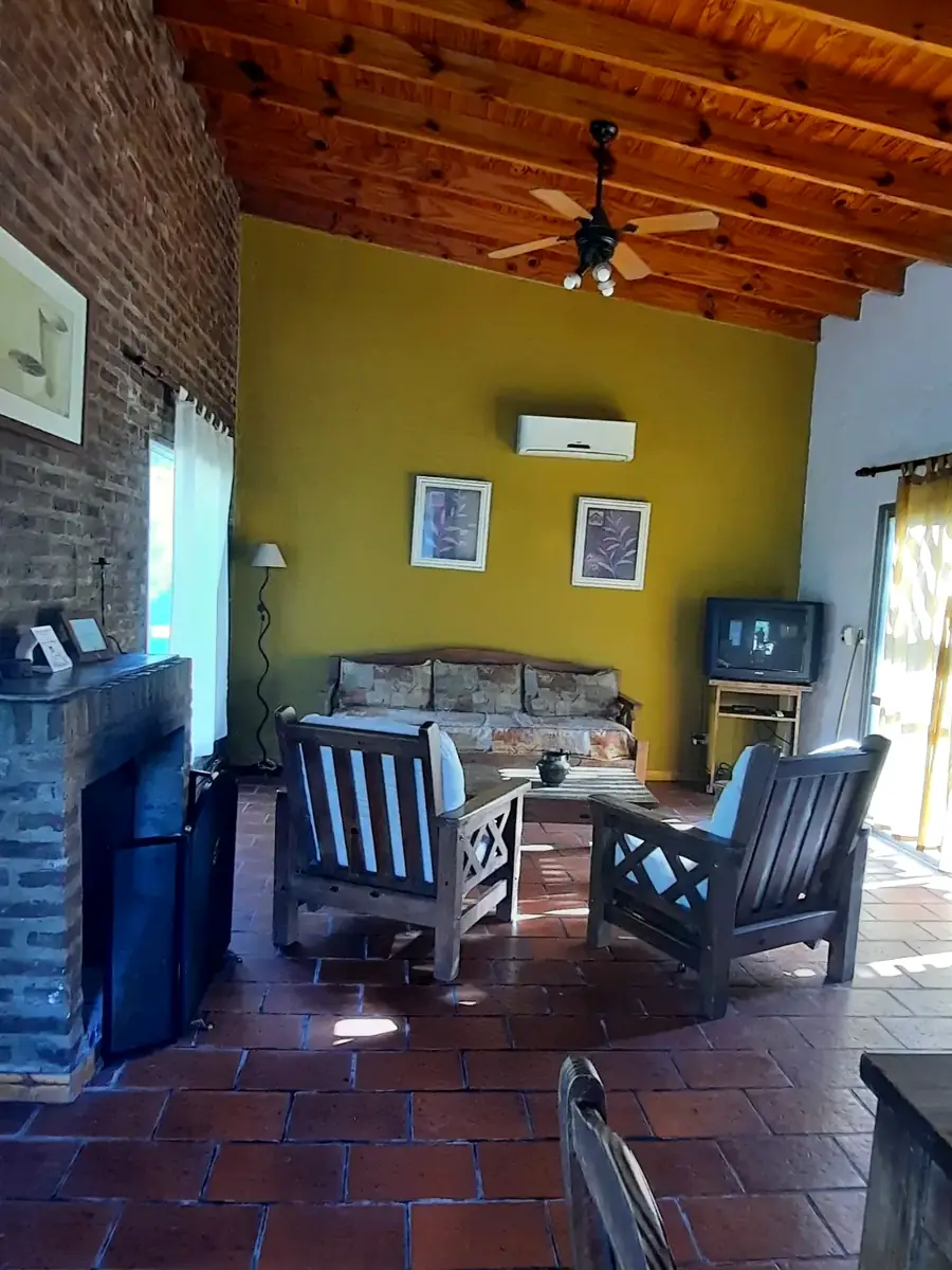 El living con hogar a leña y pared de ladrillo, en El Ombú.